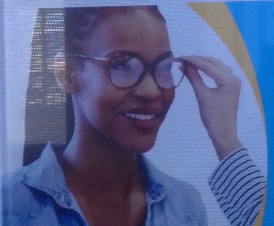 A patient smiling while trying on a new pair of glasses at Eldora Eye and Optical Centre
